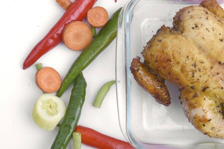 Roasted chicken in glass baking tray with vegetables isolated over white backgroundの写真素材