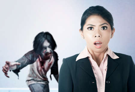 Asian businesswoman scared looking at zombies inside the building. Halloween conceptの写真素材