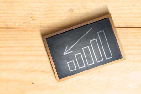 Graph with arrow down on the chalkboard. Global economic crisisの写真素材