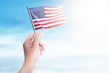 Hands holding an American flag with a blue sky background. Happy Labor Day