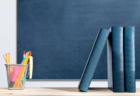 Desk with a row of books and pencil in a stationery basket with a chalkboard background. Back to...