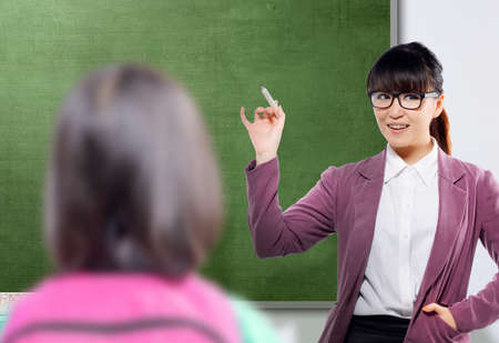 Asian teacher woman with marker standing in the classroom with a chalkboard background. Back to School conceptの写真素材