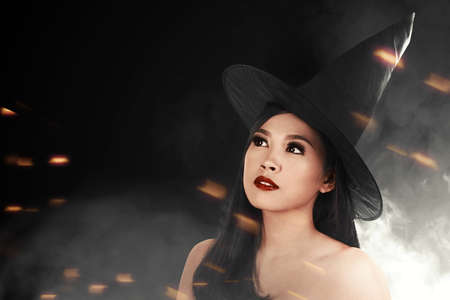 Asian witch woman with hat standing with black backgroundの写真素材