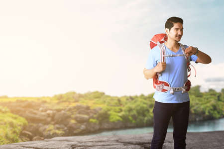 Asian man with a backpack with a lake view and blue sky background. World Tourism Dayの写真素材