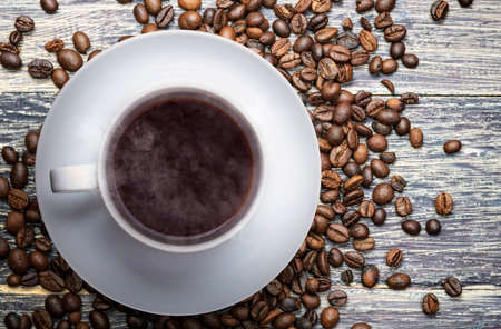 The cup of hot coffee with coffee beans on the table. International Coffee Day