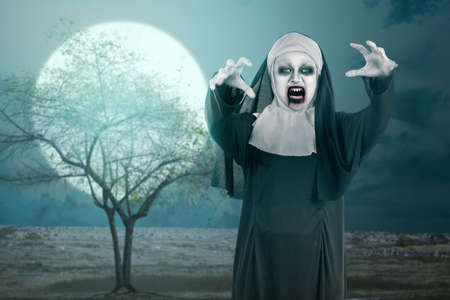 Scary devil nun standing with a night scene backgroundの写真素材