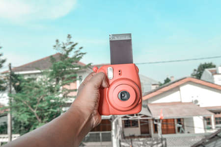 Human hands holding a camera with a blue sky backgroundの写真素材