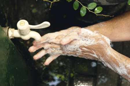 Man washing his hands with soap and running water at outdoor