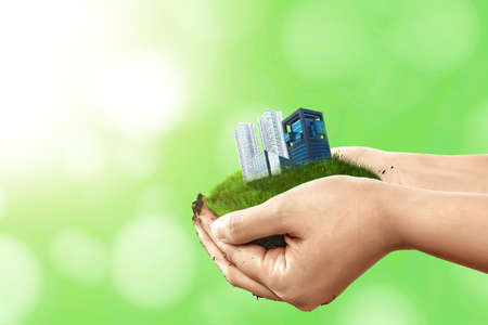 Human hand holding land with buildings and apartments. World Habitat Dayの写真素材