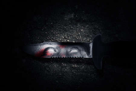 Bloody knife with zombie shadow on the blade with a grunge wall background. Halloween concept