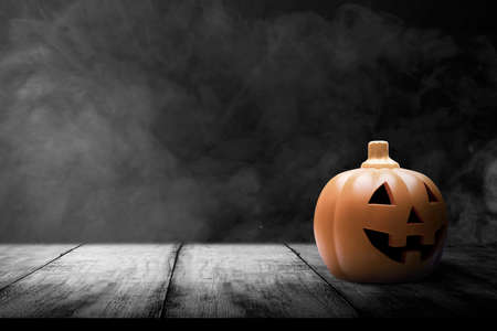 Jack-o-Lantern on wooden table with smoke and dark backgroundの写真素材
