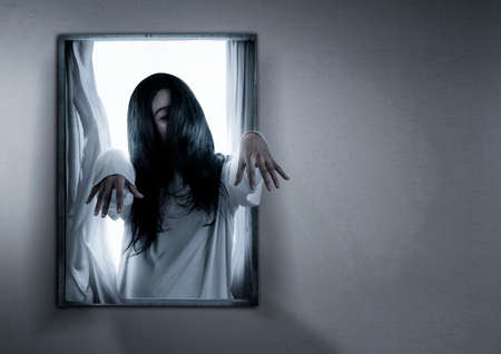 Scary ghost woman standing on the window in the abandoned house. Halloween conceptの写真素材