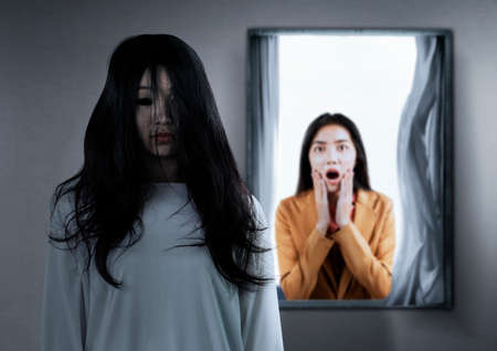 Asian businesswoman scared looking at a scary ghost woman in the abandoned house. Halloween concept