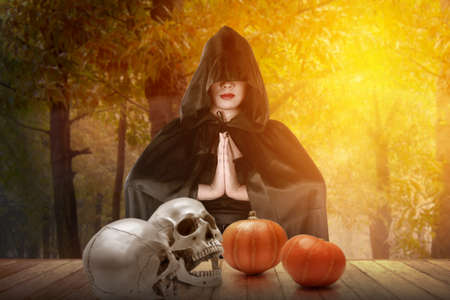 Asian witch woman with a cloak standing with a forest backgroundの写真素材