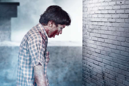 Scary zombie with blood and wound on his body standing in the abandoned buildingの写真素材