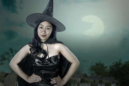 Asian witch woman with a hat standing with the night scene backgroundの写真素材