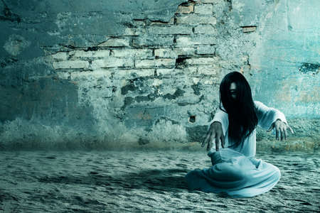 Scary ghost woman crawling with a cracked wall background. Halloween conceptの写真素材