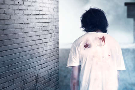 Scary zombie with blood and wound on his body standing in the abandoned building