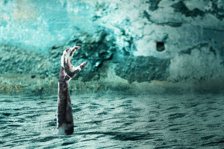 Zombie hand with blood and wound raised from the groundの写真素材