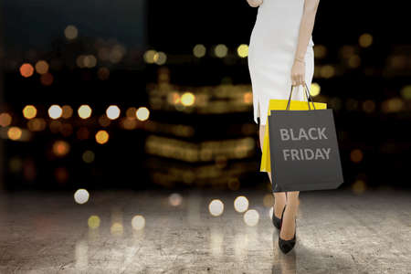 Women carrying a shopping bag with a blurred light background. Black Friday concept