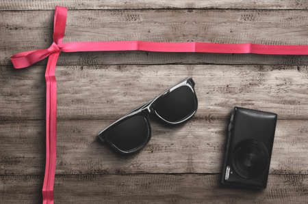 Eyeglasses and camera with red ribbon on wooden background. Cyber Monday conceptの写真素材