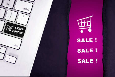 Cyber Monday text on the laptop keyboard with a ripped paper showing sale text. Cyber Monday concept