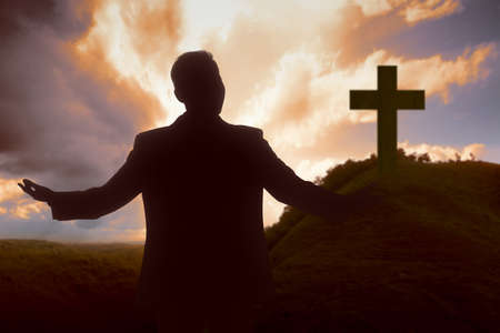 Silhouette of businessman raised hands and praying to god with a sunset sky background