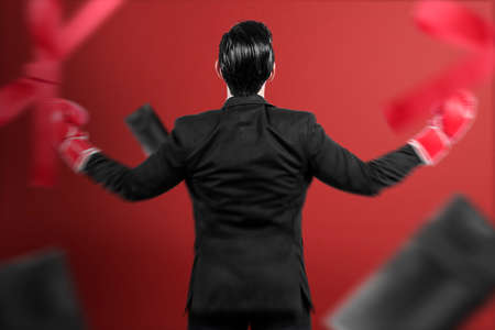 Rear view of Asian businessman with boxing gloves celebrate boxing day sale with red backgroundの写真素材