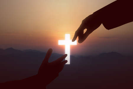 Jesus Christ giving a helping hand to human with a sunset sky backgroundの写真素材