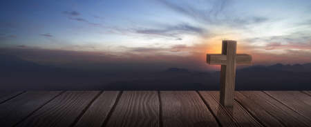 Christian cross on the wooden floor with a sunrise sky backgroundの写真素材