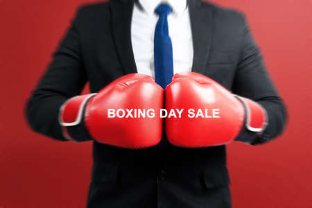 Businessman with boxing gloves celebrate boxing day sale with red backgroundの写真素材