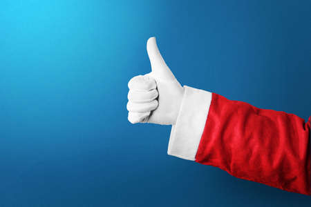 Santa Claus hand showing thumbs up gesture with a colored background. Merry Christmasの写真素材