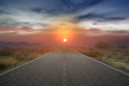 Asphalt road with green grass and sunrise sky backgroundの写真素材