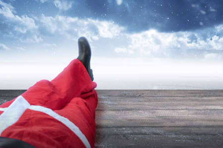 Santa Claus lying on wooden floor with snowfall background. Merry Christmas