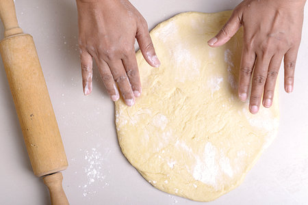Hands making dough with a rolling pin on the table