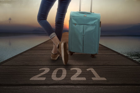 2021 on a wooden pier and traveler woman with a suitcase. Happy New Year 2021の写真素材