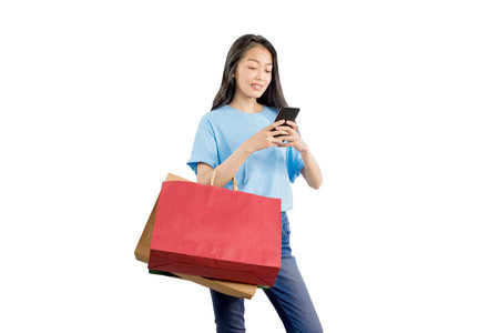 Asian woman carrying shopping bags holding mobile phone isolated over white backgroundの写真素材