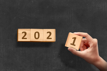 Hand changes the wooden cube from 2020 to 2021. Happy New Year 2021