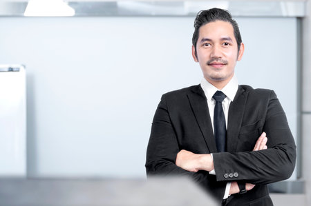 Asian businessman standing with crossed arms on the office roomの写真素材