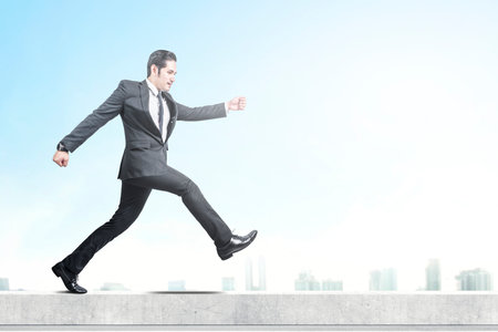 Asian businessman walking on the rooftop with a blue sky backgroundの写真素材