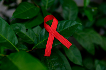 Red ribbon on the green leaf. World Cancer Day conceptの写真素材