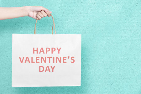 Human hand holding shopping bags with a colored background. Valentines dayの写真素材