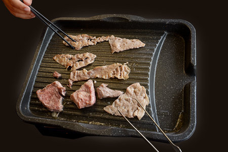 People grilling korean barbeque on the restaurantの写真素材