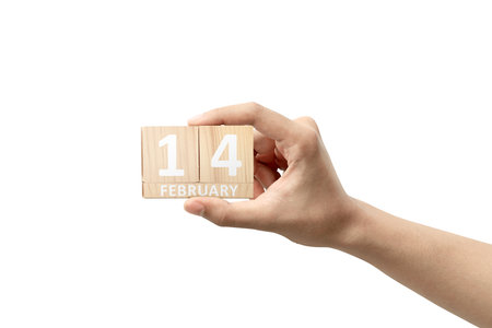 Human hand holding wooden cube with 14th February sign isolated over white background