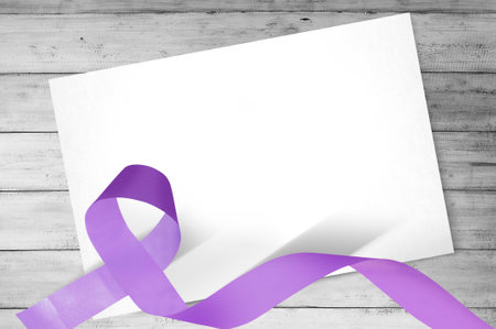 Purple ribbons with blank white paper on wooden background. World Cancer Day concept. Blank white paper for copy spaceの写真素材