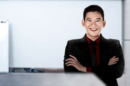 Asian businessman standing with crossed arms on the office room