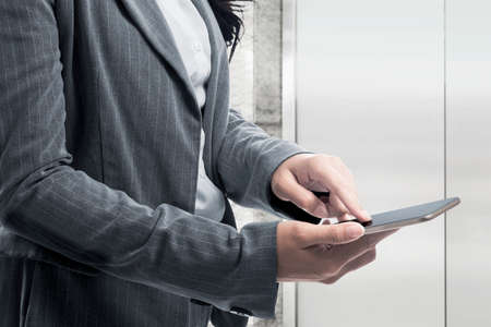 Businesswoman standing while using smartphone on the office roomの写真素材