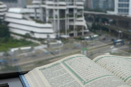 Quran open beside the window with cityscapes background