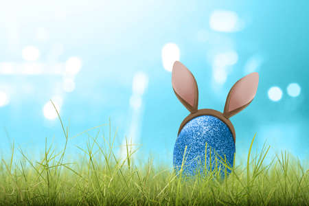 Blue easter eggs with bunny ears on the green grass. Happy Easterの写真素材