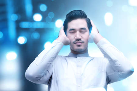 Asian Muslim man in praying position (salat) with blurred light backgroundの写真素材